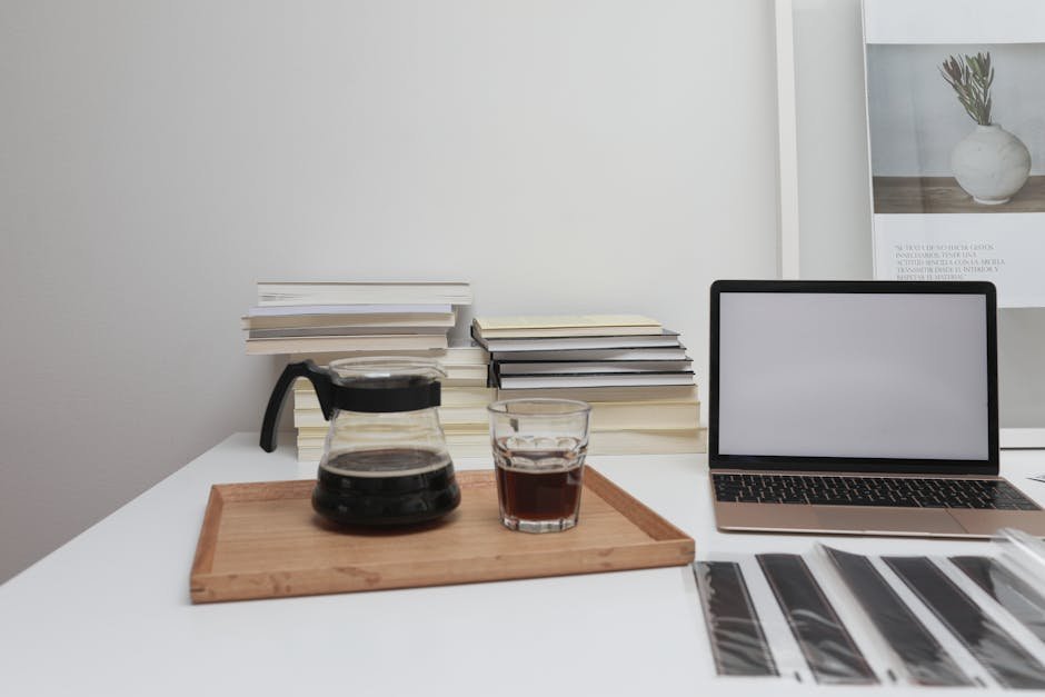 A tidy office desk setup with coffee, laptop, and books. Ideal for modern workspace inspiration.