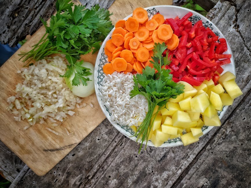 A colorful assortment of fresh vegetables and rice arranged on a rustic wooden table.