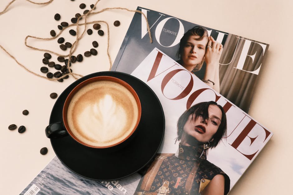 A cozy cafe table with a latte and Vogue magazines, perfect for stylish relaxation.