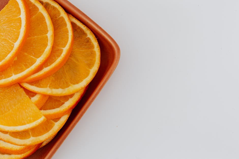 Top view of fresh orange slices arranged on a terracotta plate with ample copyspace.
