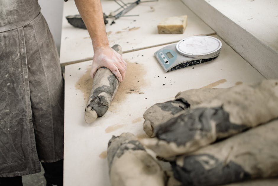 Artist molding clay pieces on a workbench in a serene pottery studio setting.