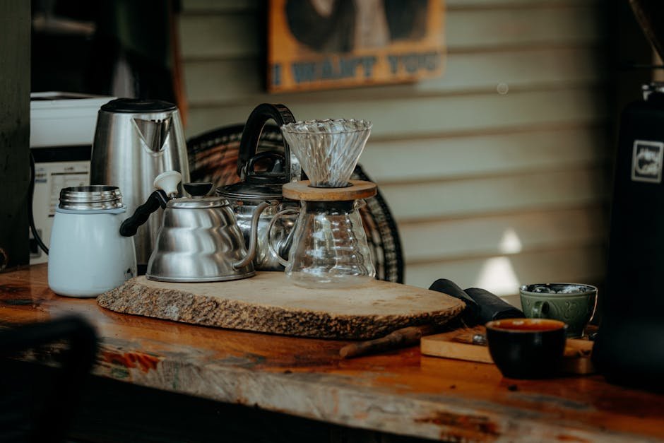 Cozy coffee brewing setup with kettles and cups on a rustic wooden table.