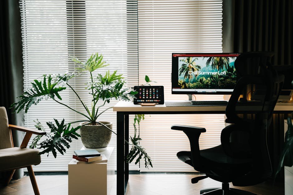 Stylish home office featuring large plant, computer setup, and minimalist aesthetic.