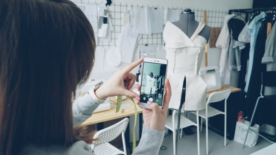 Fashion designer captures dress design using smartphone in atelier.